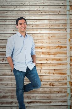 Smiling casual man standing against faded pine wooden planks