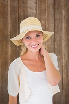 Attractive young blonde smiling at camera in sunhat against wooden planks background
