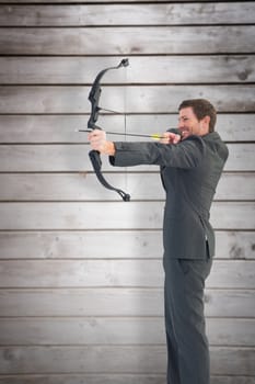 Businessman shooting a bow and arrow against wooden planks