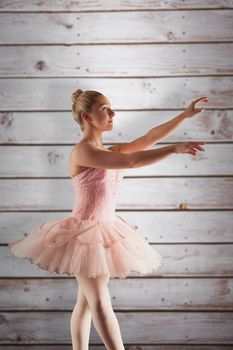 Pretty ballerina in pink  against wooden planks