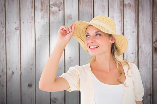 Attractive young blonde smiling in sunhat against wooden planks