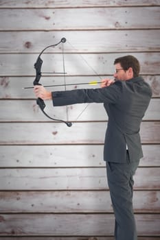 Businessman shooting a bow and arrow against wooden planks