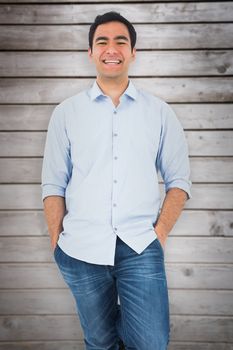 Smiling casual man standing against wooden planks