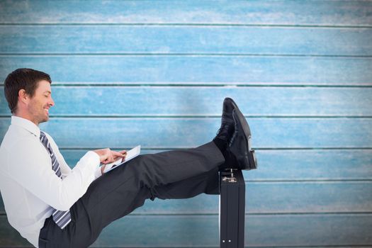 Businessman with feet up on briefcase against wooden planks