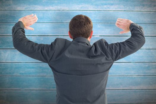 Businessman standing with hands up against wooden planks