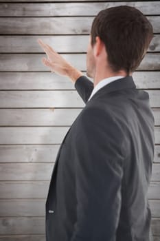 Focused businessman standing and pointing against wooden planks