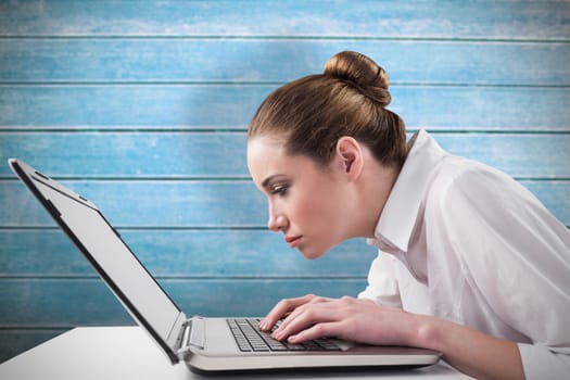 Attentive businesswoman typing on laptop against wooden planks