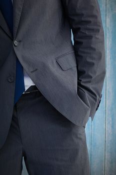 Businessman standing with hand in pocket against wooden planks