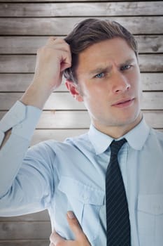 Thinking businessman scratching head against wooden planks