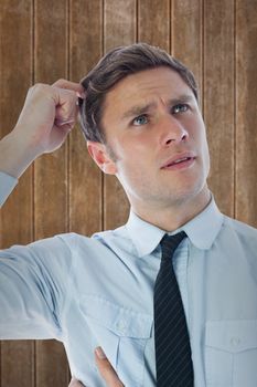 Thinking businessman scratching head against wooden planks background