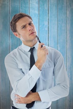 Thinking businessman holding pen against wooden planks