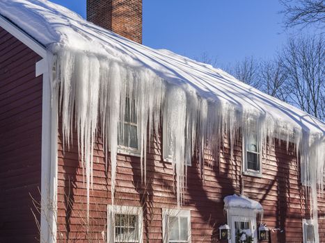 Ice dams and snow on roof and gutters after bitter cold in New England, USA