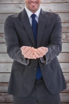 Smiling businessman presenting with hands against wooden planks