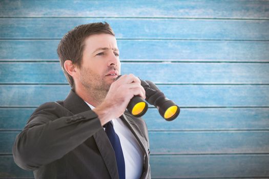 Focused handsome businessman holding binoculars against wooden planks