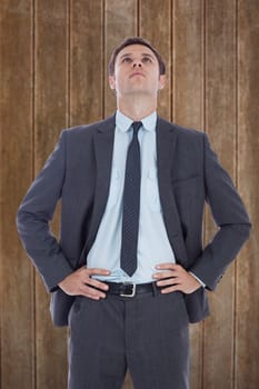 Serious businessman with hands on hips against wooden planks background