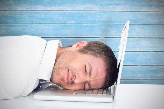 Tired businessman resting on laptop against wooden planks