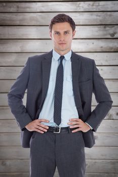 Serious businessman with hands on hips against wooden planks