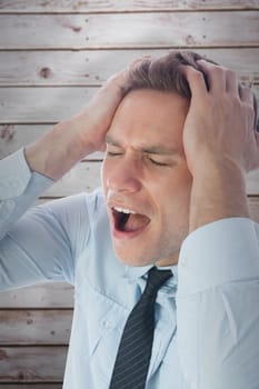 Stressed businessman with hands on head against wooden planks