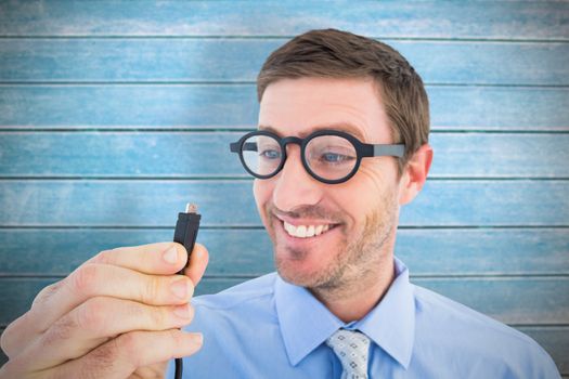 Geeky businessman holding a cable against wooden planks