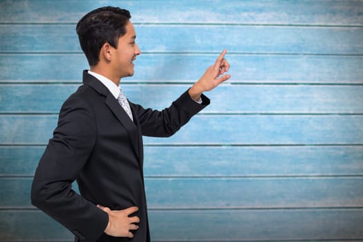 Smiling asian businessman pointing against wooden planks