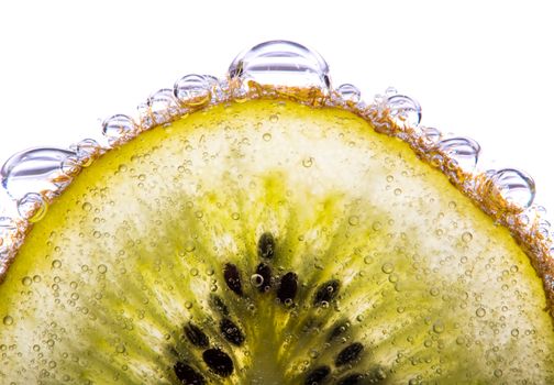 Close up shot of a fresh kiwi situated in carbonated water surrounded by bubbles.