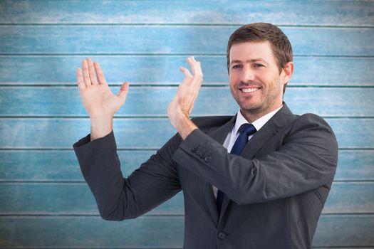 Smiling businessman showing something with his hands against wooden planks