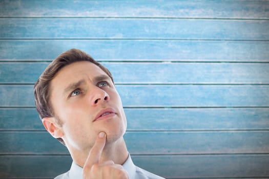 Thinking businessman with finger on chin against wooden planks