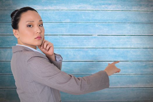 Thoughtful asian businesswoman pointing against wooden planks