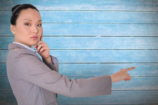 Thoughtful asian businesswoman pointing against wooden planks