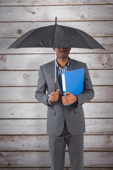 Businessman standing under umbrella against wooden planks