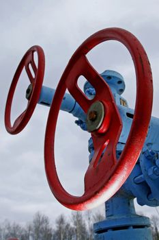 Two steel pipeline with red valves against blue sky