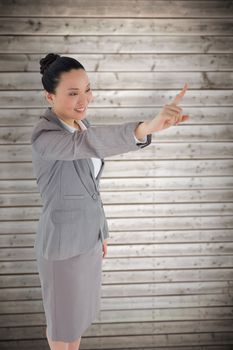 Smiling asian businesswoman pointing against wooden planks background
