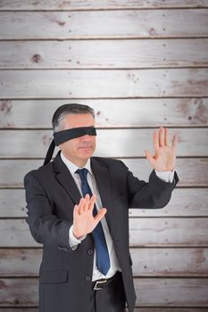 Mature businessman in a blindfold against wooden planks