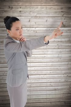 Unsmiling thinking asian businesswoman pointing against wooden planks background