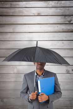 Businessman standing under umbrella against wooden planks