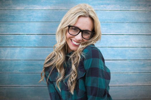 Pretty blonde smiling at camera against wooden planks