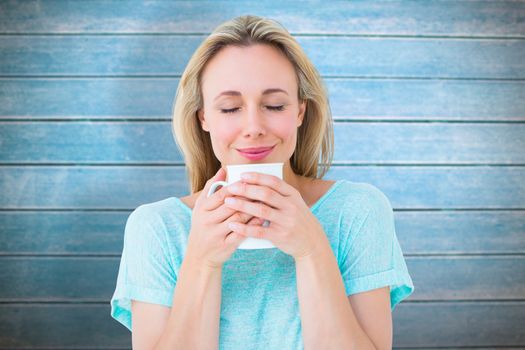 Cheerful blonde holding mug of hot drinking against wooden planks