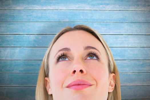 Close up of smiling blonde woman looking up against wooden planks