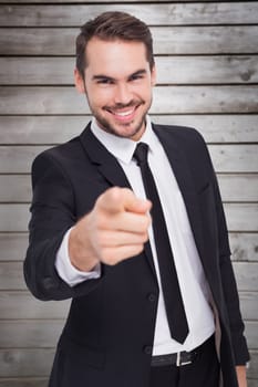 Happy businessman pointing at camera against wooden planks