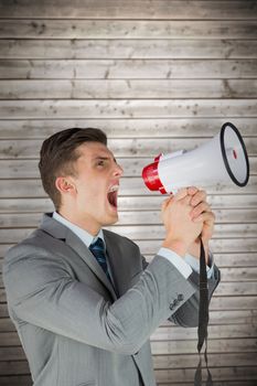 Businessman with megaphone against wooden planks background