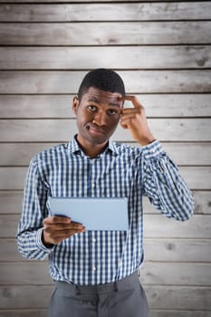 Young businessman thinking and holding tablet against wooden planks