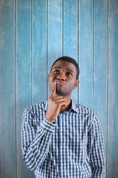 Young businessman thinking against wooden planks