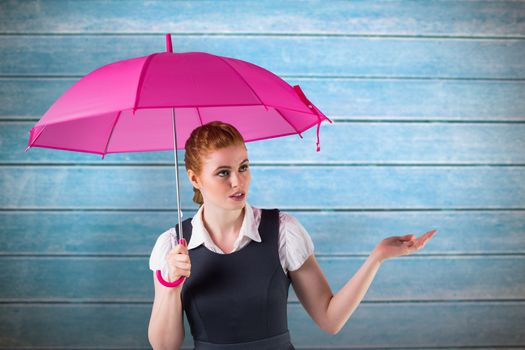 Pretty redhead businesswoman holding umbrella against wooden planks