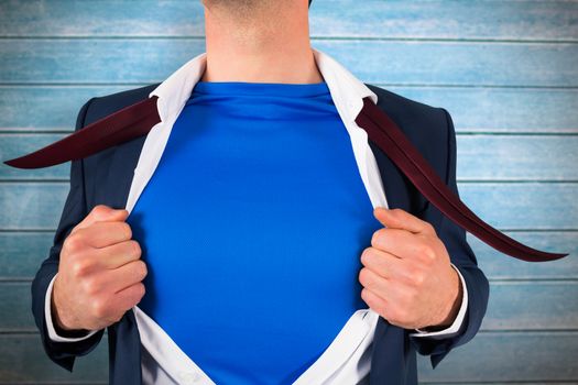 Businessman opening his shirt superhero style against wooden planks