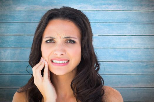 Pretty brunette with a toothache against wooden planks