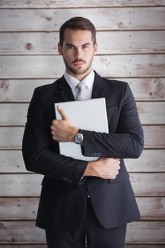 Businessman in suit posing with his laptop  against wooden planks