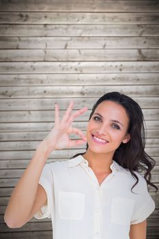 Pretty brunette making ok sign against wooden planks background