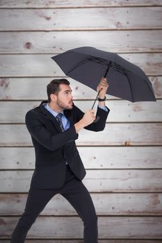 Businessman holding umbrella to protect himself against wooden planks
