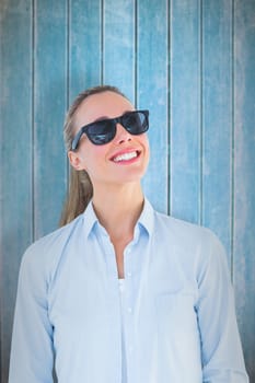Portrait of smiling blonde wearing sunglasses against wooden planks
