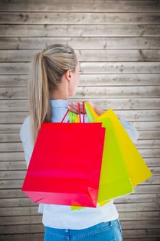 Pretty blonde holding shopping bags against wooden planks background